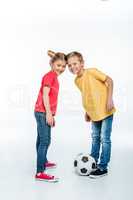 siblings standing with soccer ball