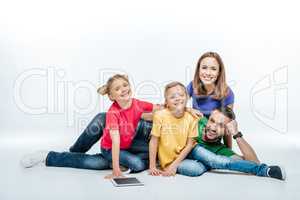 family lying together with digital tablet