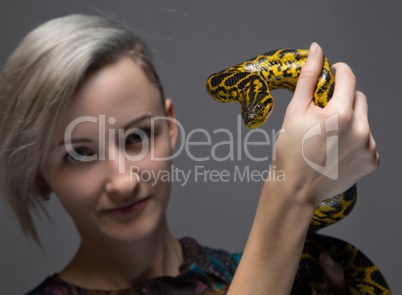Young blond woman holding yellow anaconda