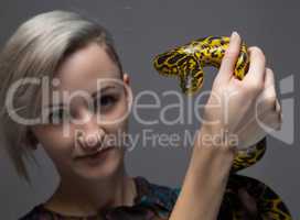 Young blond woman holding yellow anaconda