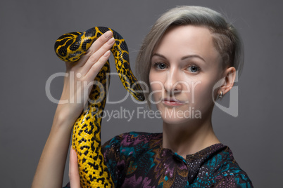 Blond woman holding yellow anaconda