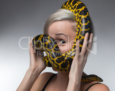 Blond woman and strangling yellow anaconda