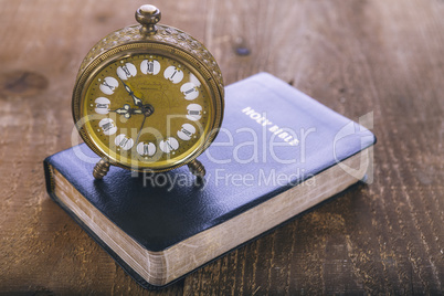 Holy Bible and old alarm clock on wood table