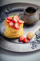 Stack of sweet pancakes with strawberry and honey.