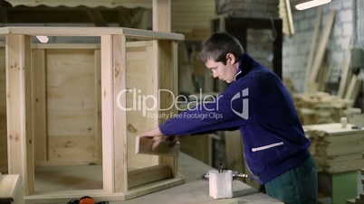 Carpenter applying glue on wooden plank with brush