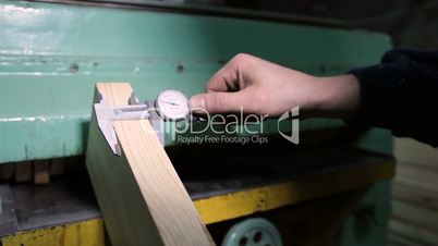 Carpenter with calipers measuring wood in workshop