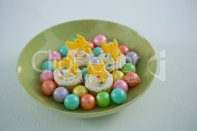 Colorful chocolate Easter eggs with cup cakes in bowl