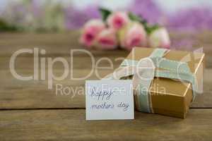 Gift box with happy mother day card on wooden surface