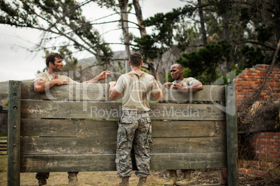 Soldier climbing wooden wall in boot camp