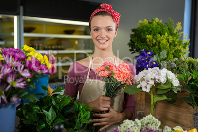 Female florist holding bunch of flower in flower shop