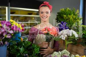 Female florist holding bunch of flower in flower shop