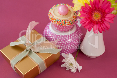 Close-up of gift box, cupcake and flowers vase