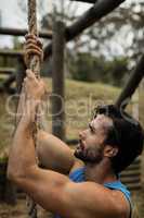 Determined man climbing a rope during obstacle course