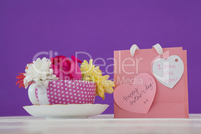 Close-up of paper bag with message and fresh flowers