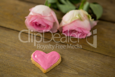 Pink roses with heart shape cookies on wooden plank