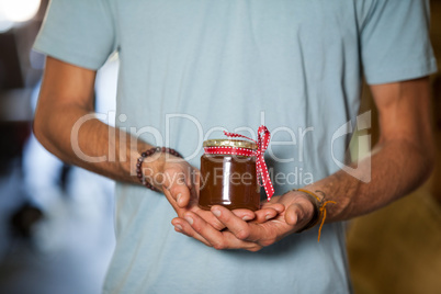 Mid-section of man holding a jar of jam