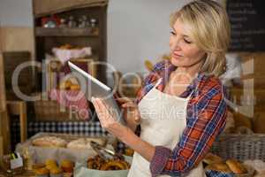 Smiling female staff using digital tablet at counter