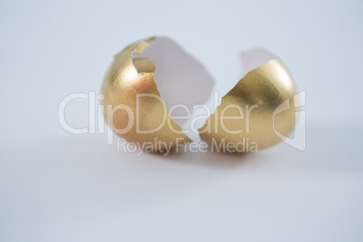 Broken golden Easter egg on white background