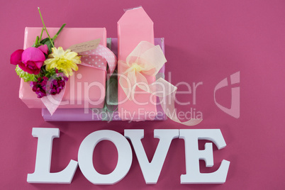 Gift boxes with flowers and text love against pink background