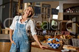 Portrait of female staff standing with hand in pocket near counter