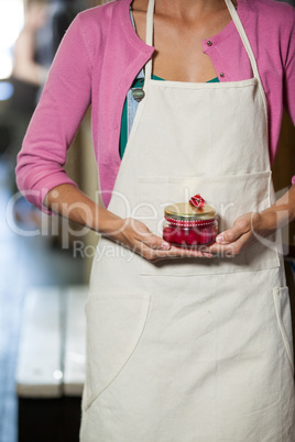 Mid-section of staff holding jar of maraschino cherry