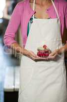 Mid-section of staff holding jar of maraschino cherry