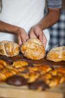 Mid-section of woman holding bread at counter