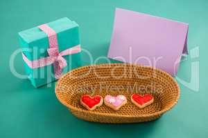 Gift box, heart shape cookies and blank card against green background