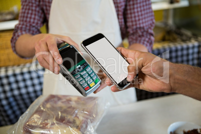Mid section of man paying through nfc technology at counter