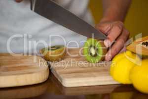 Mid-section of male staff cutting kiwifruit at organic section