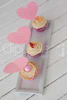 Close-up of three delicious cupcakes with heart shape cards in tray