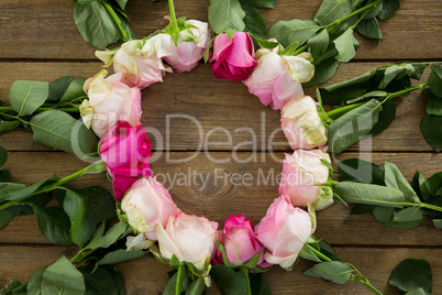 Pink roses arranged in round shape on wooden plank