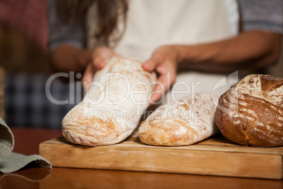 Mid-section of woman holding bread at counter