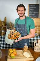 Portrait of male staff holding basket of pretzel at counter