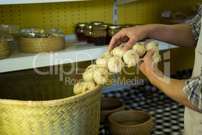 Mid-section of staff putting garlic in wicker basket
