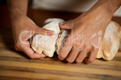 Male staff tearing a bun in bakery shop