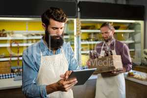 Attentive staff using digital tablet at bakery counter
