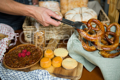 Staff holding pretzel with tong in bakery shop
