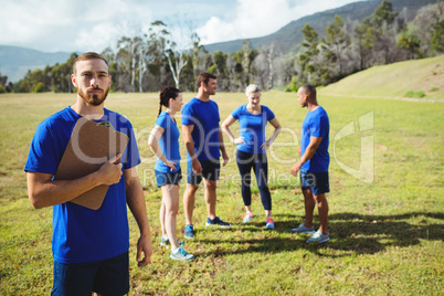 Fit man standing and holding a clipboard in boot camp