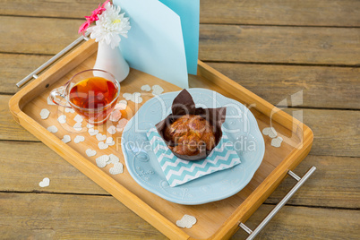 Cupcake, tea, flower vase and card in tray