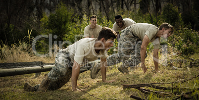 Soldiers crawling under the net during obstacle course