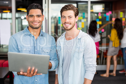 Portrait of happy male executives using laptop