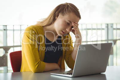 Sad schoolgirl looking at laptop in library
