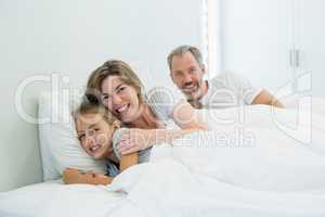 Happy family lying together on bed in bedroom at home