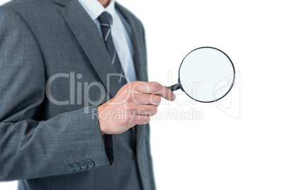 Mid section of businessman holding magnifying glass