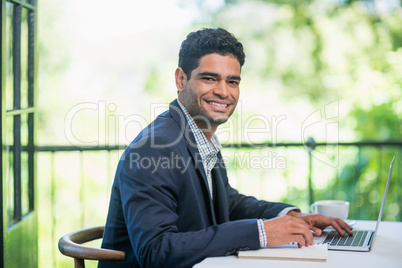 Happy businessman using laptop in a restaurant