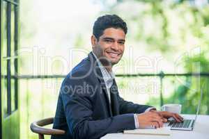 Happy businessman using laptop in a restaurant
