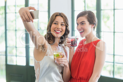 Friends taking a selfie while holding cocktail glasses