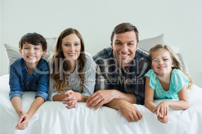 Portrait of smiling family lying on bed in bedroom