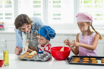 Mother and kids preparing cookies in kitchen